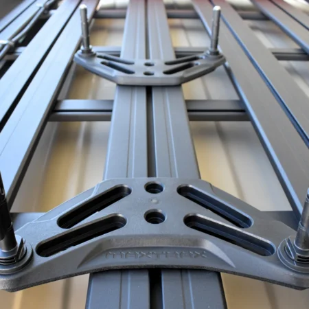 Close-up of a roof rack crossbar system with a central mounting bracket and bolts on metal rails.