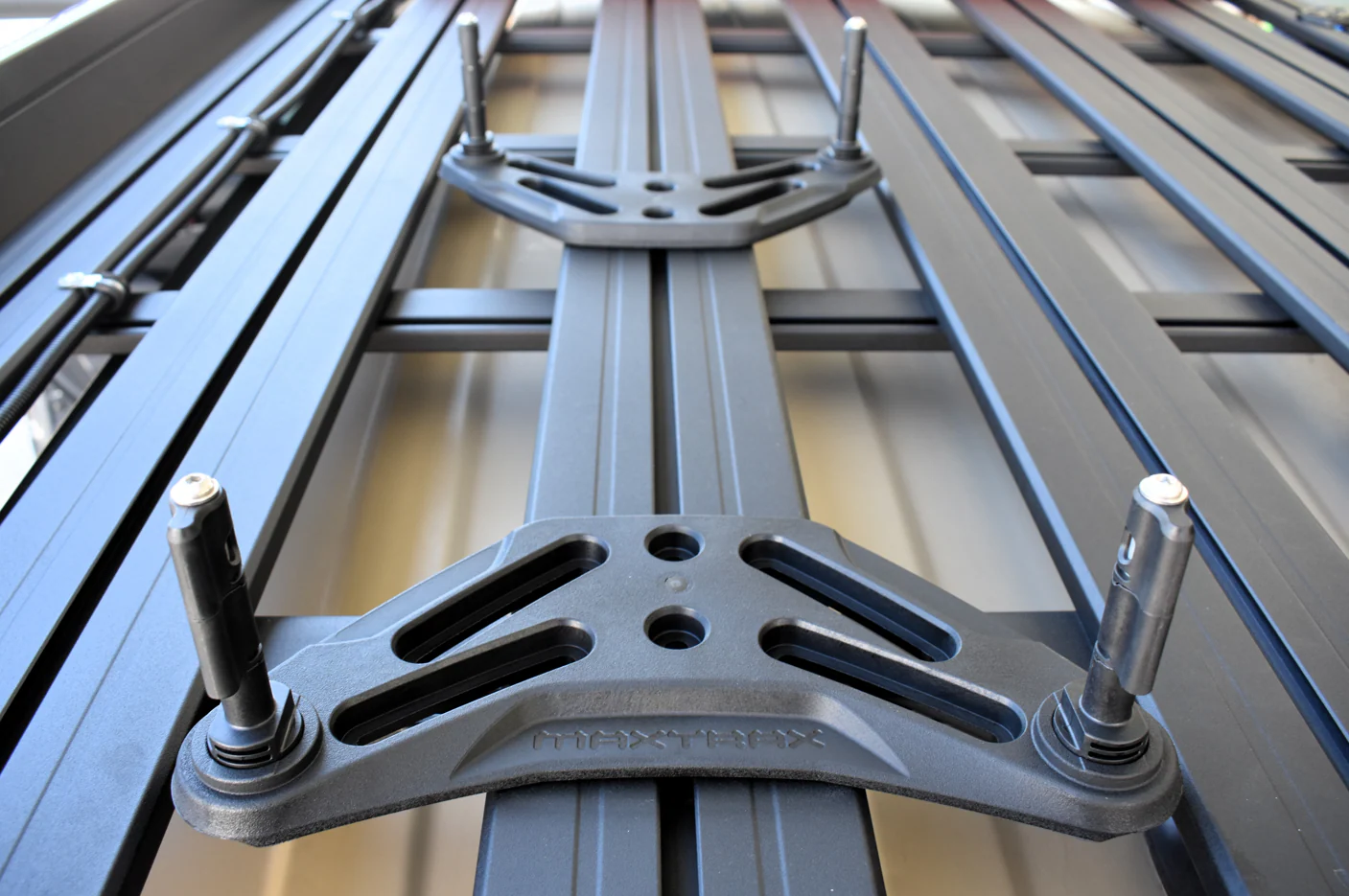 Close-up of a roof rack crossbar system with a central mounting bracket and bolts on metal rails.